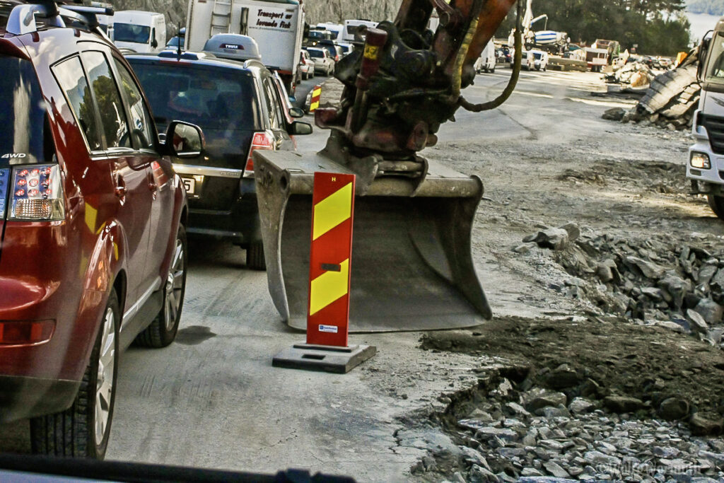 Sehr schlechte Baustellenabsicherung. Baggerschaufel zwischen dem fließenden Verkehr.