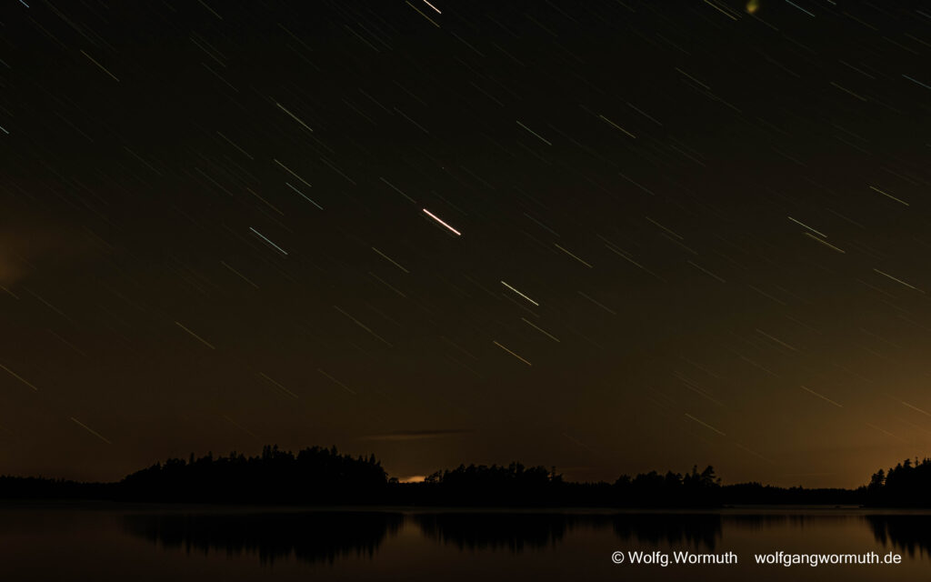 Low-Key-Bild, Langzeitaufnahme, 525 s. Sterne sind Striche am Himmel und übern See.