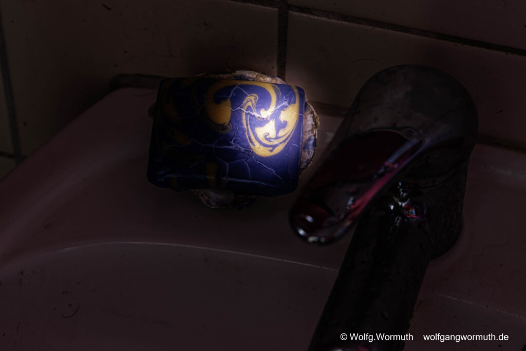 Aus einer selbstgemachten Seife, eine Wenezianische Maske zu erkennen. Sie schaut am Waschbecken zu.