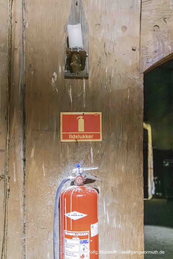 Kerze überm Feuerlöscher der mit Kerzenwachs betropft ist im Wikingermuseum in Trellegorg Dänemark. Gut zu erkennen, Museum ist aus Holz.